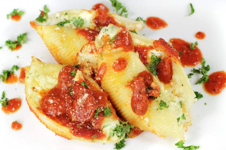 Prendi una pirofila e sporca il fondo con qualche cucchiaiata di sugo. Dopodiché, farcisci un conchiglione alla volta con il composto di ricotta e spinaci. Versa ancora un po’ di sugo sopra e spolvera la superficie con una manciata di parmigiano grattugiato. Infine inforna a 200 gradi, modalità ventilata, per 20 minuti e, trascorso il tempo necessario, tira fuori i tuoi conchiglioni ripieni e portali in tavola belli caldi o tiepidi.