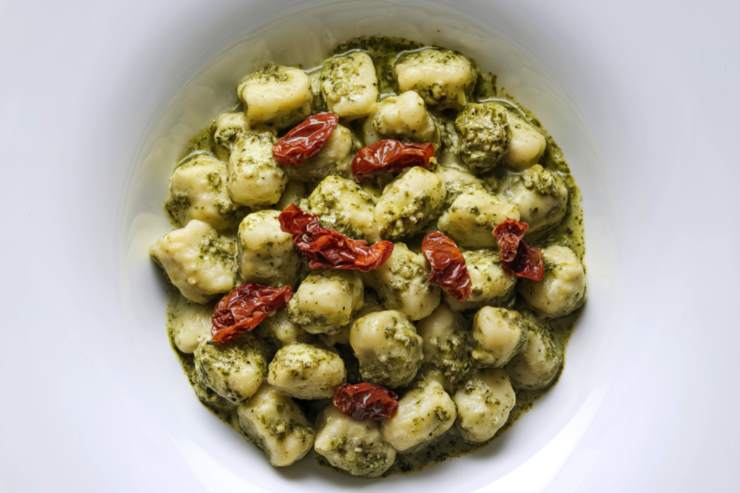 Raggiunto il punto di bollore, cala gli gnocchi e cuocili qualche minuto, fino a quando non saranno venuti a galla. Scolali e trasferiscili con una schiumarola all’interno di una insalatiera, aggiungi il pesto e completa l’opera con i pomodorini secchi spezzettati. Infine, impiatta e porta in tavola.