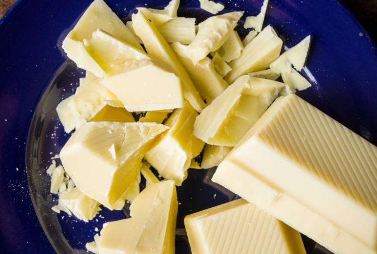 Riversiamo il burro in un tegame e sciogliamo a bagnomaria, intanto tritiamo il cioccolato bianco finemente;