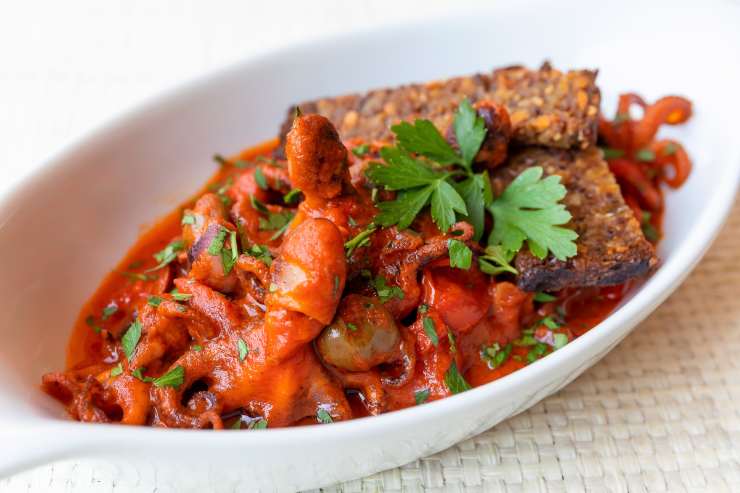 Nel frattempo, pulisci il polpo eliminando il becco e gli occhi e rimettilo nel sugo. Dai una mescolata e impiatta in un vassoio da portata con una spolverata di prezzemolo fresco tritato al coltello.