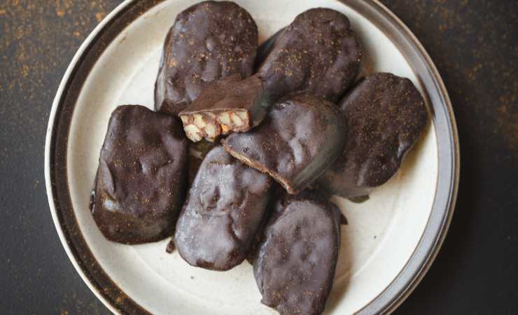 Trita il cioccolato fondente grossolanamente con il coltello e fallo sciogliere a bagnomaria o nel microonde. Quando questo sarà tiepido immergi la parte superiore dei biscotti e poi mettili ad asciugare su una gratella per un’oretta prima di gustarli insieme ad amici e parenti.