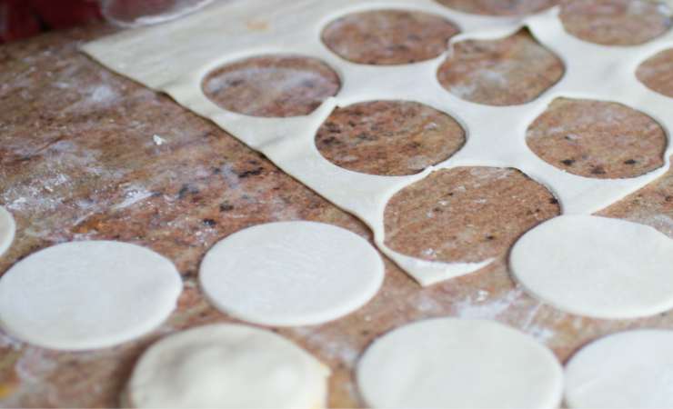 Su metà di questi versa un cucchiaio di passata di pomodoro condita con un pizzico di sale ed un filo d’olio extravergine d’oliva, un po’ di besciamella e qualche cubetto di mozzarella. Chiudi tutto con l’altra metà di dischetti e sigilla i bordi con le dita oppure premendo con un coppa pasta più piccolo, senza però tagliare la pasta.