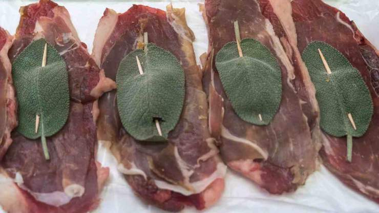 Appiattite le fettine di vitello con il batticarne, rendendole sottili e regolari: adagiate su ciascuna fetta una foglia di salvia ed una fettina di prosciutto crudo. Chiudete e fermate tutto con uno stecchino, infilandolo per tenere fermi prosciutto e salvia.