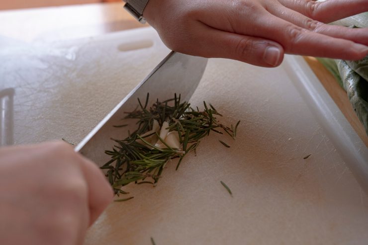 Per prima cosa, prendi il rosmarino, elimina il legnetto, e tritalo al coltello insieme alla salvia, agli spicchi d’aglio e alla scorza di limone grattugiata, in modo da ottenere un mix bello sottile.