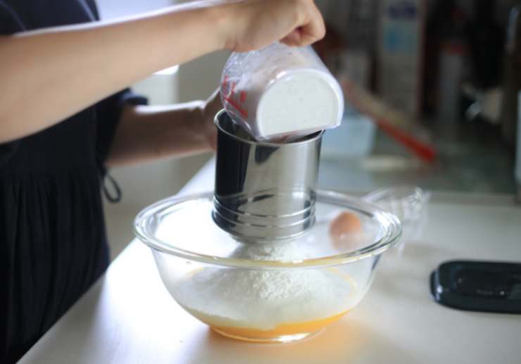 Spremiamo ora il succo di limone e filtriamolo, quindi inglobiamo anche questo nella crema. A questo punto dovremo procedere a setacciare, poco alla volta, le polveri: farina, lievito e vanillina;