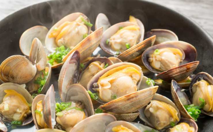 Lasciamo in ammollo le vongole un paio d’ore, quindi procediamo a scolarle e sgocciolarle per bene. In una padella larga e capiente rosoliamo l’aglio e il peperoncino (possiamo eliminare i semi per un risultato meno intenso) e lasciamo dorare. Uniamo le vongole e copriamo con un coperchio. Nel giro di un paio di minuti al massimo le vongole dovrebbero aprirsi tutte. Spegniamo quindi la fiamma;