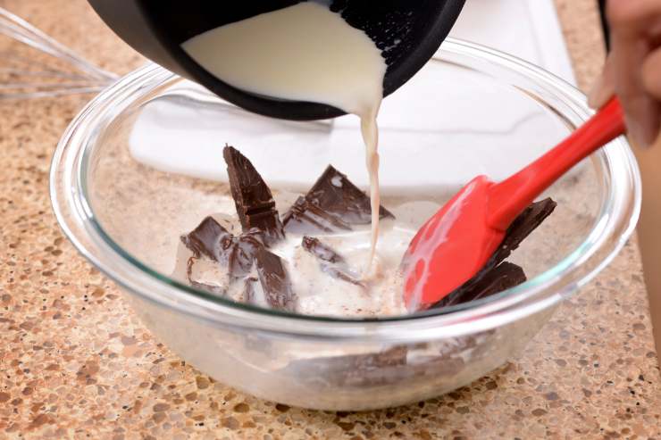 A questo punto, riduci in scaglie il cioccolato fondente e metti sul fuoco la panna con lo zucchero a velo. Quando sfioreranno il punto di bollore, togli tutto dal fornello ed aggiungi il cioccolato. Mescola bene finché il composto non si sarà sciolto, fallo raffreddare e poi mettilo in frigo per 30 minuti.