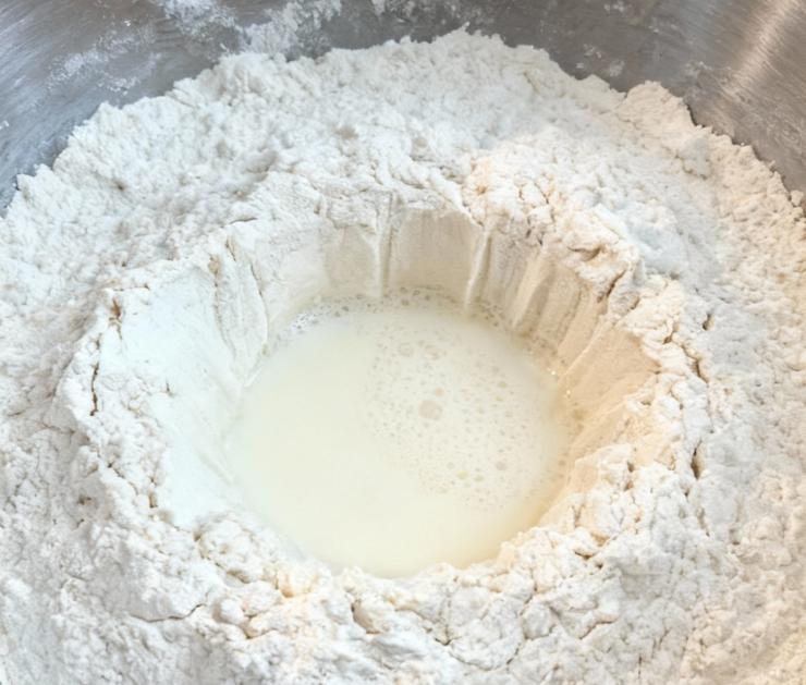 Iniziate sciogliendo un cubetto di lievito di birra nel latte tiepido, insieme ad un cucchiaino raso di zucchero. Versate la farina nel boccale della planetaria ed aggiungete la miscela di latte e lievito poco alla volta iniziando ad impastare con il gancio a bassa velocità.