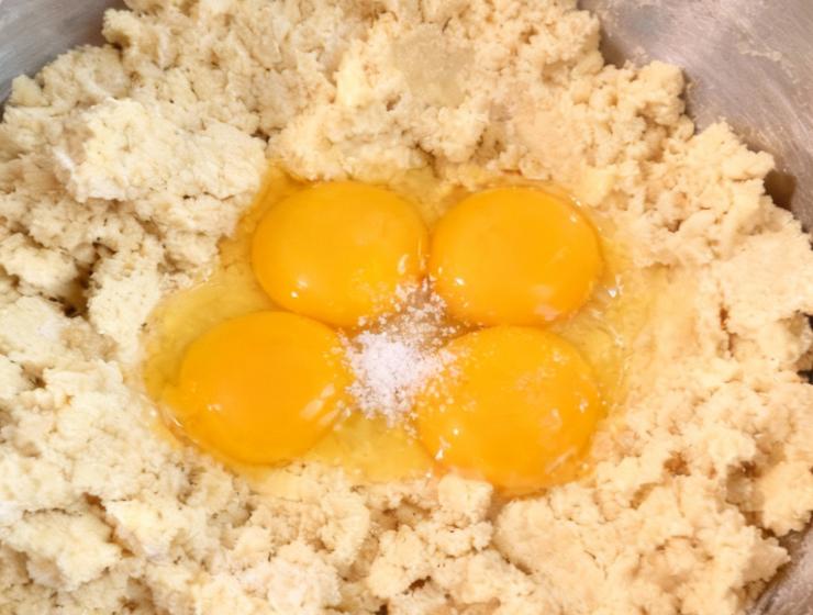 Unite ora l’olio di semi, il parmigiano reggiano ed il pecorino grattugiati: continuate a lavorare fino ad ottenere un impasto grezzo e quasi asciutto. Fatto ciò unite le uova ed un cucchiaio raso di sale, proseguite con la planetaria fin quando saranno completamente incorporate.