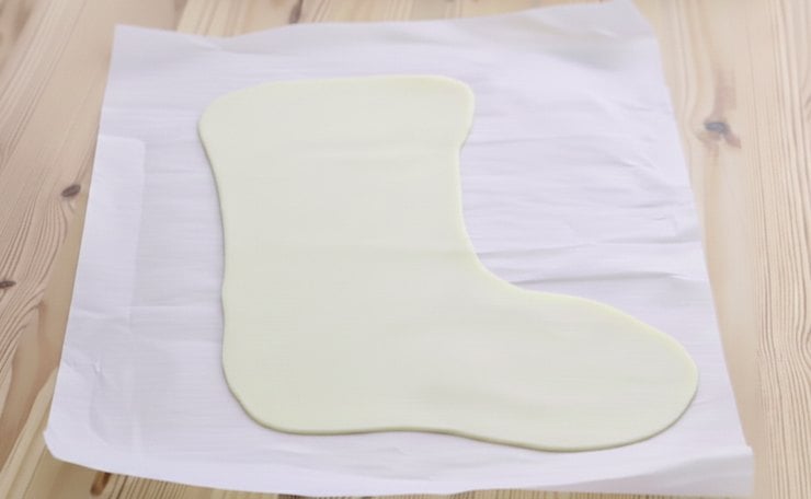 Con un coltello appuntito, ritagliate la forma di una calza della Befana, quindi bucherellate la superficie con i rebbi di una forchetta. Aprite poi il secondo rotolo e tagliate un’altra calza di sfoglia delle stesse dimensioni della prima. Disponete sulla prima calza la farcitura di prosciutto e scamorza, lasciando circa mezzo centimetro dal bordo.