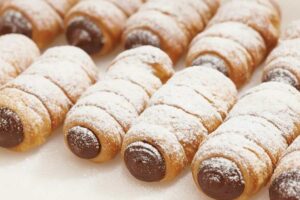 cannoli di pasta sfoglia con cioccolato e ricoperti di zucchero a velo