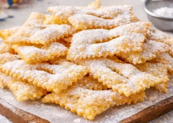 Chiacchiere di Carnevale fatte in casa croccanti e piene di bolle, spolverizzate con zucchero a velo.