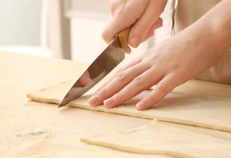 Stendiamo il rotolo di sfoglia su di una superfice piana e tagliamo 6 strisce nel senso della lunghezza;
