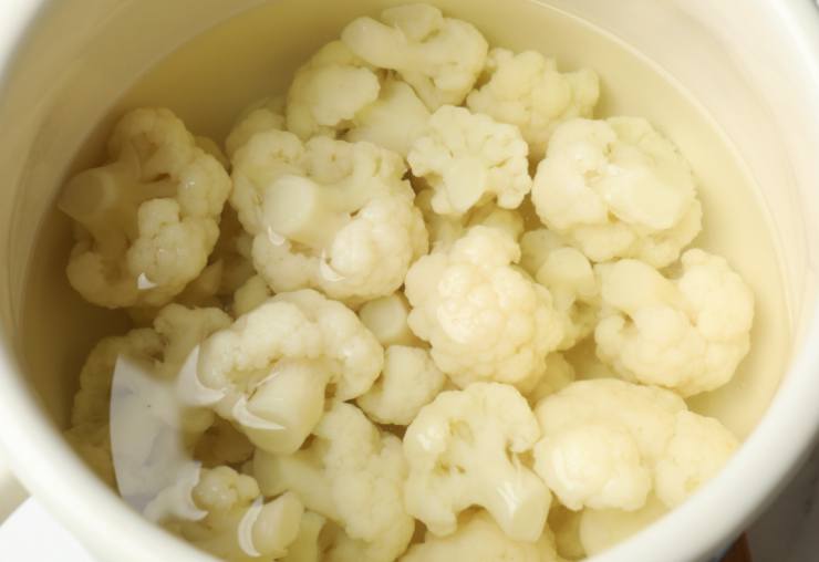 Lasciamo soffriggere qualche minuto e accorpiamo le cimette. Facciamo rosolare pochi istanti e togliamo l’aglio. Ricopriamo con acqua a pelo e poi con un coperchio. Facciamo cuocere il cavolfiore fino a quando non sarà bello tenero. Riduciamo in crema con un frullino a immersione;