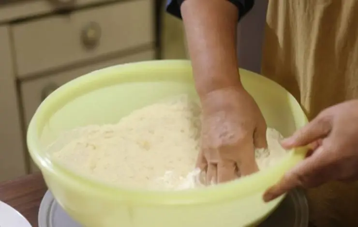 Riversiamo la farina in una ciotola e uniamo la polvere di mandorle. Accorpiamo lo zucchero e il pisto, quindi aggiungiamo un pizzico di ammoniaca per dolci. Amalgamiamo gli ingredienti;