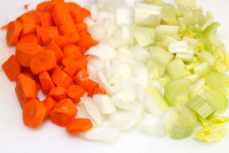 Laviamo e peliamo le carote e tritiamole. Puliamo il sedano e sminuzziamo e facciamo lo stesso con la cipolla. Riversiamo il trito di carote, sedano e cipolla in una padella capiente e dai bordi alti insieme ad un filo d’olio d’oliva e rosoliamo qualche minuto;