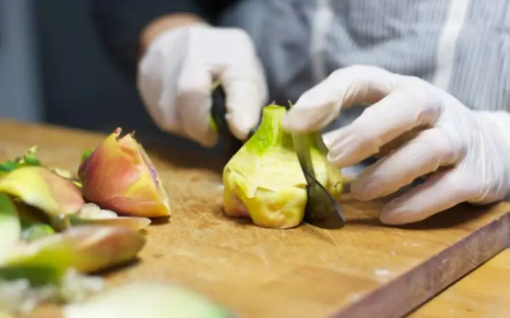 Per iniziare dobbiamo dedicarci a pulire i carciofi: tolte le foglie più esterne passiamo a tagliare il gambo e, man mano che procediamo, immergiamoli in una ciotola con acqua e un limone tagliato a spicchi;