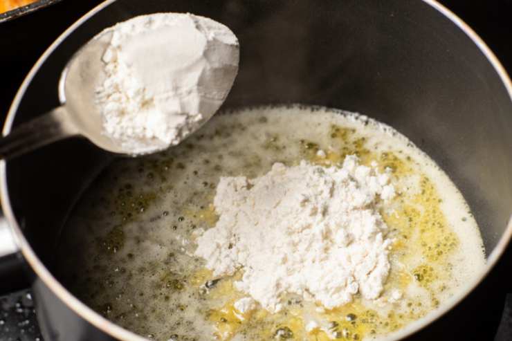 Uniamo la farina al burro fuso e iniziamo a mescolare con un mestolo di legno fino ad ottenere una sorta di pallina compatta, quindi uniamo il latte caldo a filo e mescoliamo a fiamma dolce fino a quando non avremo ottenuto una crema omogenea (possiamo usare un frullino per sciogliere eventuali grumi). Insaporiamo con sale e noce moscata a nostro gusto;