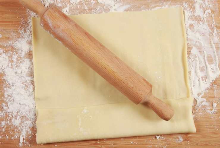 Andiamo a stendere il rotolo di sfoglia su di una superficie piana e dal rettangolo ritagliamo 10 strisce seguendo il senso della lunghezza (ogni striscia sarà larga circa un centimetro). Andiamo ora ad avvolgere ogni striscia attorno all’apposito stampo per cannoli o, se non lo abbiamo, attorno alla carta stagnola a cui avremo dato la stessa forma.