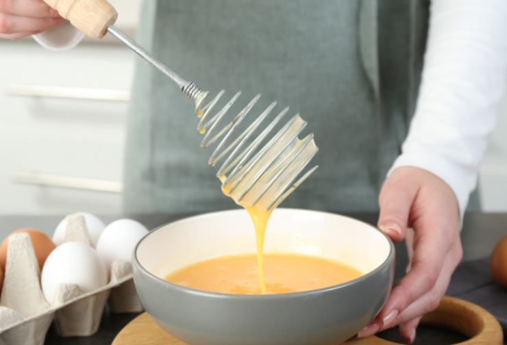 In una ciotola andiamo a rompere le uova e sbattiamole con il parmigiano grattugiato. Accorpiamo il pizzico di lievito istantaneo e lavoriamo ancora;