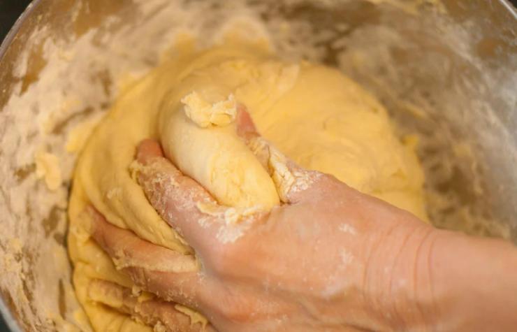 A questo punto procediamo a setacciare nei liquidi la farina e il lievito e lavoriamo prima con un mestolo e poi a mano fino ad ottenere un panetto senza grumi, liscio ed elastico;