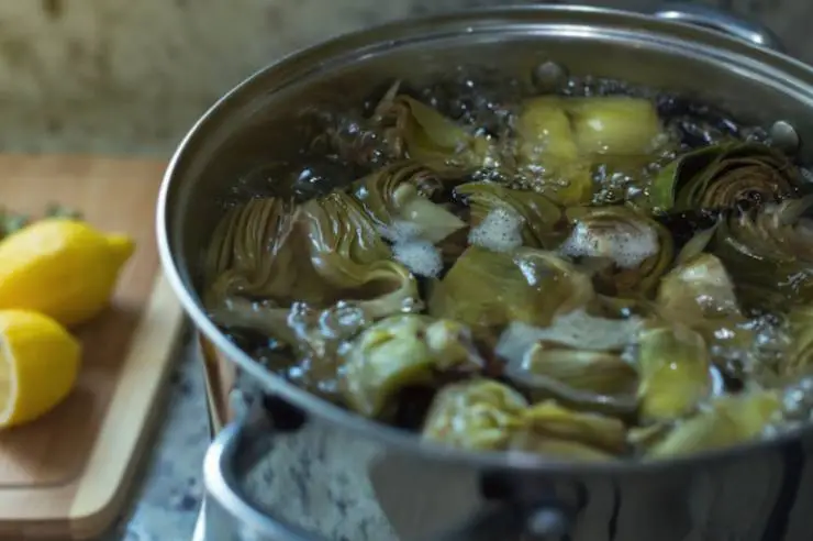 Puliti tutti i carciofi immergiamoli in un tegame con acqua e portiamo sul fuoco per lessarli: insaporiamo con un pizzico di sale e lasciamo bollire per intenerirli, ma facciamo attenzione a non cuocerli troppo, non devono sfaldarsi;