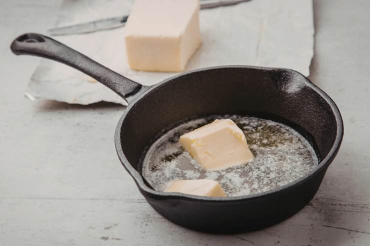 Riversiamo i biscotti secchi al cacao in un frullatore e riduciamoli in briciole (teniamone da parte una porzione). Intanto sciogliamo il burro a bagnomaria, quindi lasciamolo intiepidire;