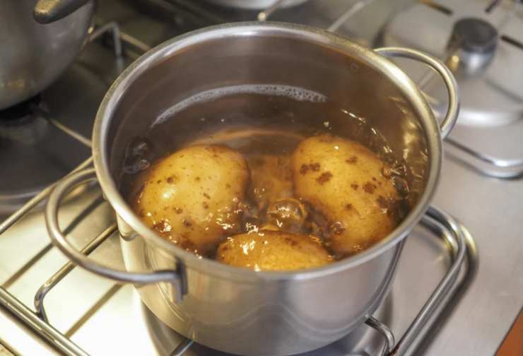 Iniziamo lavando le patate e sbucciandole, quindi immergiamole in una pentola con acqua salata e portiamo a bollore sul fuoco: inteneriamole senza sfaldarle, quindi scoliamole;