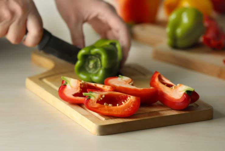 Per iniziare dovremo dedicarci alla pulizia e al taglio dei peperoni: affettiamoli ed eliminiamo semi e filamenti dopo averli lavati, quindi tamponiamo via l’acqua in eccesso;