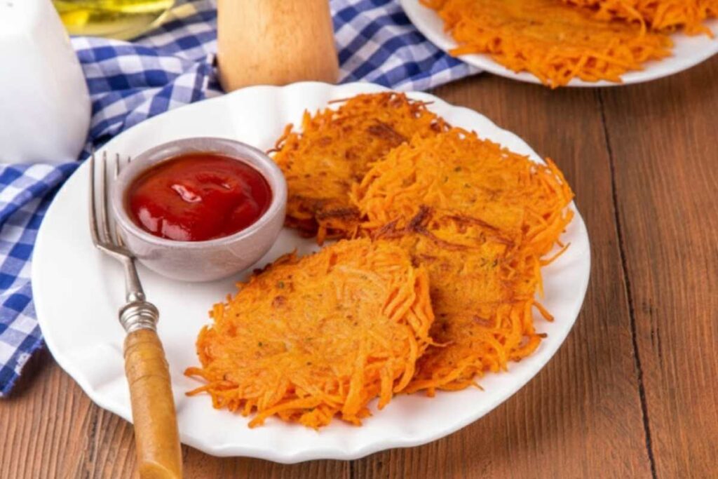 rosti di carote in piatto con ciotola di ketchup