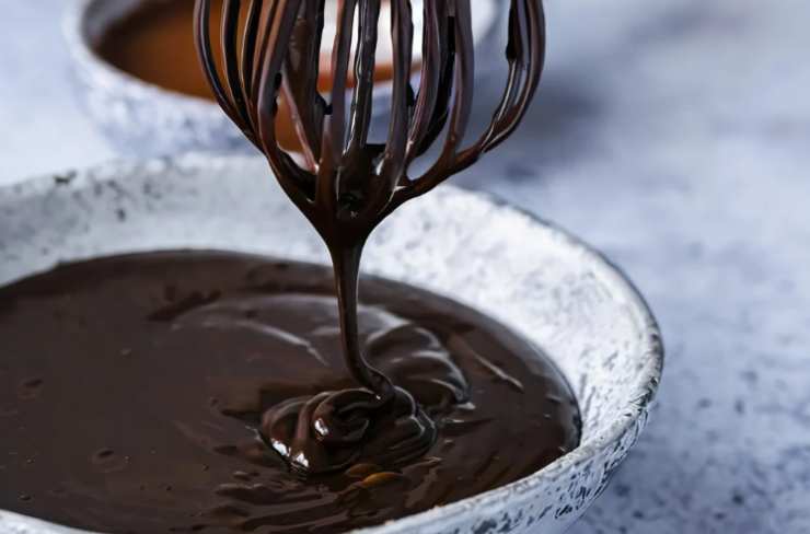 Cuociamo a 160 gradi per circa un’ora. Intanto dedichiamoci alla copertura: riversiamo la panna in un tegame e facciamo arrivare a bollore. Uniamo il cioccolato fondente tritato e mescoliamo fino a sciogliere, quindi spegniamo la fiamma;