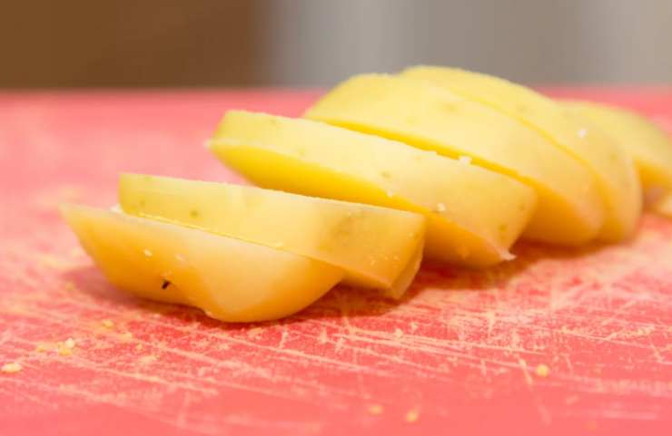 Andiamo ora a tagliare le patate lesse a fettine e prepariamo una pirofila da forno: sul fondo versiamo un coppino di besciamella. Distribuiamo uno strato di fettine di patate e la scamorza tagliata a pezzetti. Ricopriamo con altra besciamella e metà del parmigiano, poi ricopriamo col resto delle fettine di patate;