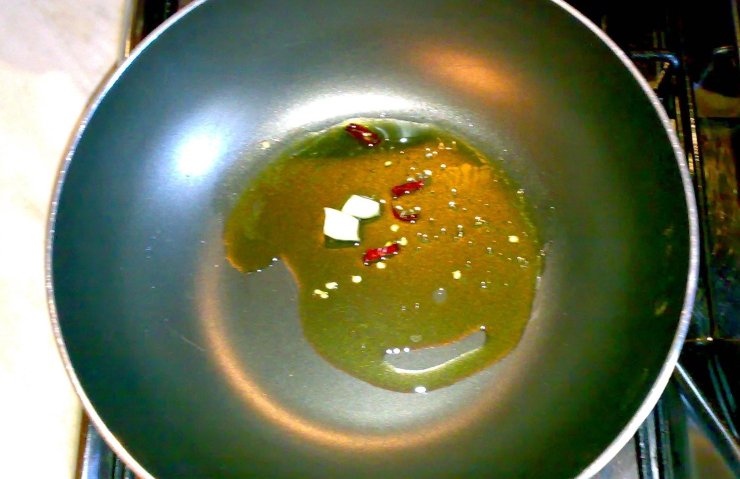 In una padella capiente, scaldate un giro generoso di olio extra vergine d’oliva con gli spicchi d’aglio schiacciati ed il peperoncino. Aggiungete i filetti di acciuga e lasciateli sciogliere a fuoco bassissimo finché si sciolgono.