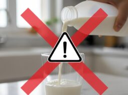 allerta-alimentare-latte-pericolo-contaminazione Una mano versa latte da una bottiglia bianca in un bicchiere di vetro, con un grande segnale di pericolo giallo sovrapposto per indicare un richiamo alimentare