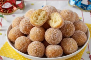 Castagnole allo yogurt sofficissime senza burro aperte a metà per mostrare la mollica alveolata e morbida su vassoio di Carnevale