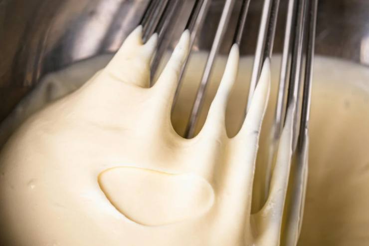 Prendiamo una ciotola capiente e versiamo la farina setacciata insieme allo zucchero e al pizzico di cannella. Aggiungiamo l’acqua a filo poco alla volta e mescoliamo con una frusta a mano finché non otteniamo una pastella liscia e senza grumi;