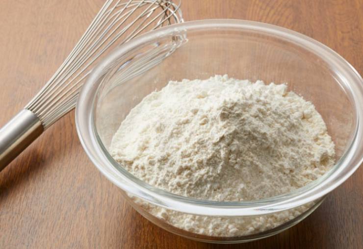 In una seconda ciotola setacciamo la farina con il lievito, quindi uniamo la vanillina e la scorza di limone grattugiata, poi lo zucchero;