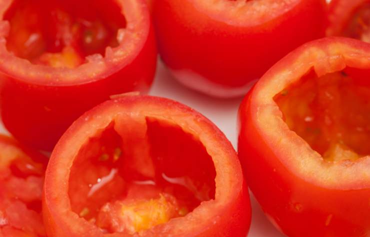 Dedichiamoci ora a lavare i pomodori, asciughiamoli e tagliamo la calotta, scavando l’interno con un cucchiaino. Uniamo la polpa al composto di carne macinata;