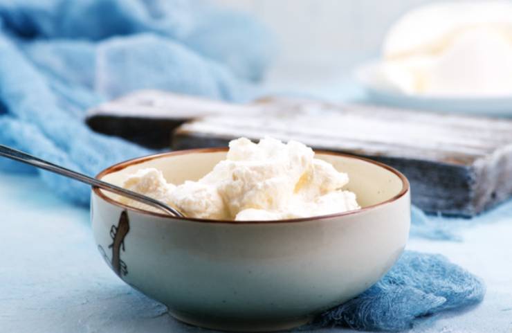 Riversiamo la ricotta sgocciolata in una ciotola e lavoriamo con una forchetta. Uniamo lo zucchero, il cacao amaro e andiamo ad amalgamare il tutto con una spatola;