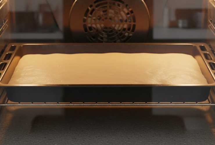 Cuociamo in forno statico a 220 gradi per 8, massimo 9 minuti. Togliamo dal forno e, senza scottarci, aiutandoci con la carta da forno sottostante, togliamo la base dalla teglia e capovolgiamo su di un ripiano (con la carta da forno sottostante). Copriamo quindi anche la parte superiore con la carta da forno e lasciamo raffreddare;