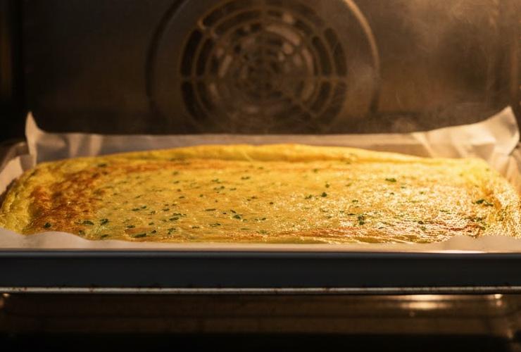 Inforniamo a 180 gradi e lasciamo cuocere per circa 15 minuti, fino a quando il rettangolo non sarà ben dorato. Sforniamo e, mentre è ancora caldo, estraiamo il rettangolo aiutandoci con la carta da forno sottostante e capovolgiamo su un secondo foglio di carta da forno;