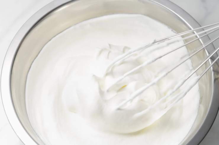 Spremiamo e filtriamo il succo di arancia e riversiamo nella crema, mescolando per amalgamare. Strizziamo la gelatina e accorpiamo anche questa alla crema, continuando a frullare. Andiamo quindi a montare la panna in una ciotola a parte;