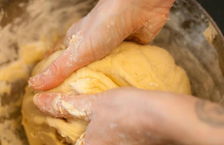 Lasciamo ammorbidire il burro a temperatura ambiente e, intanto, riversiamo in una ciotola capiente la farina e lo zucchero. Accorpiamo al centro il latte e l’acqua, poi sbricioliamo il lievito e uniamo le due uova leggermente sbattute. Iniziamo a impastare, se preferiamo prima con una forchetta e poi a mano;