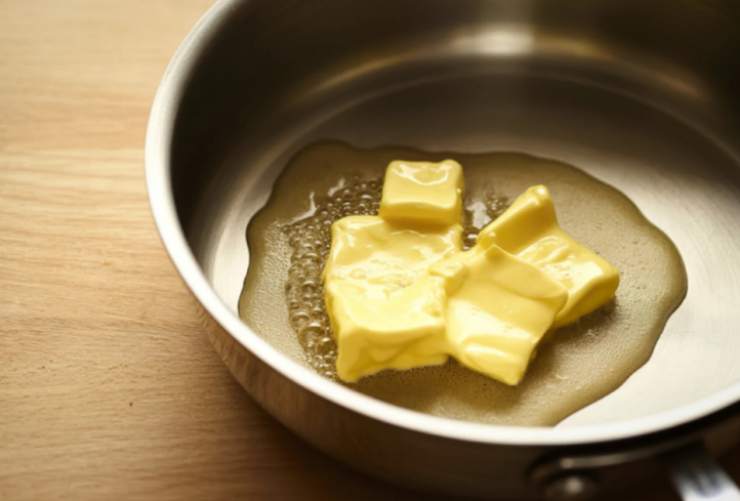 Tritiamo i biscotti secchi con un frullatore o riversandoli in un sacchetto per alimenti e schiacciando con un matterello e riduciamoli in polvere. Intanto sciogliamo il burro a bagnomaria;