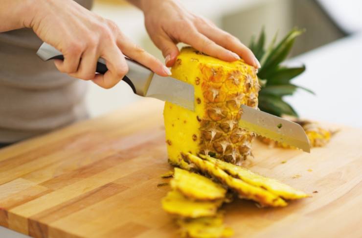Iniziamo pulendo l’ananas: eliminiamo la buccia esterna, il ciuffo e la base, poi tagliamo il frutto a fette spesse circa un centimetro e rimuoviamo il torsolo centrale;