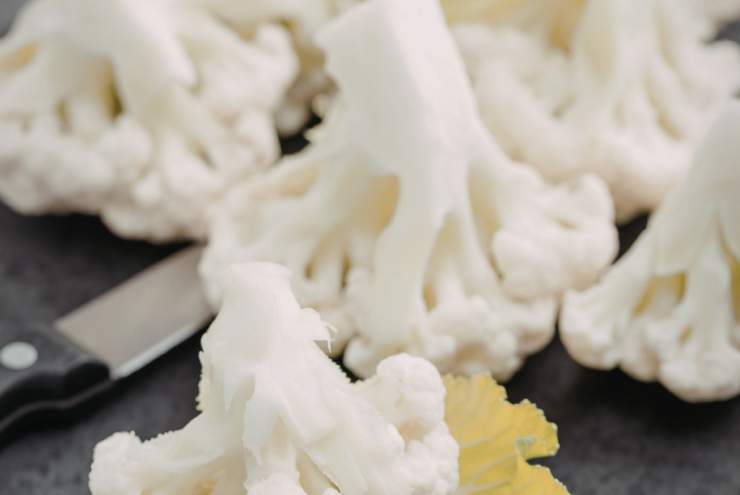 Iniziamo lavando il cavolfiore e tagliandolo a cimette. Mettiamo a sgocciolare e dedichiamoci alla pastella: in una ciotola versiamo la farina e creiamo un cratere al centro;