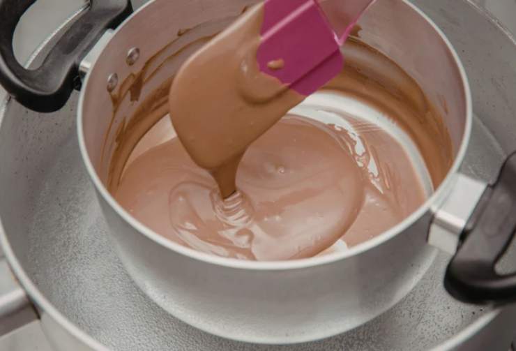 Iniziamo tritando il cioccolato fondente e riversiamo in un tegame. Portiamo sul fuoco a sciogliamo a bagnomaria;