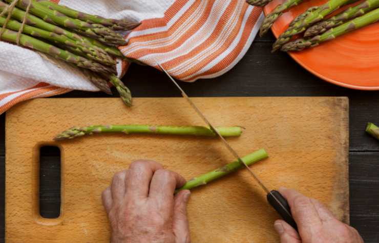 Iniziamo pulendo gli asparagi: eliminiamo la parte finale del gambo, laviamoli sotto l’acqua corrente e separiamo le punte tenere, tagliando il resto a pezzetti;