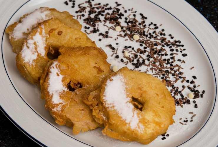 Scaldiamo l’olio di semi in una padella dai bordi alti e, quando è ben caldo, immergiamo le frittelle. Lasciamo dorare su un lato, poi giriamo e facciamo cuocere l’altro. Una volta cotte sgoccioliamole e rotoliamole nello zucchero a velo.