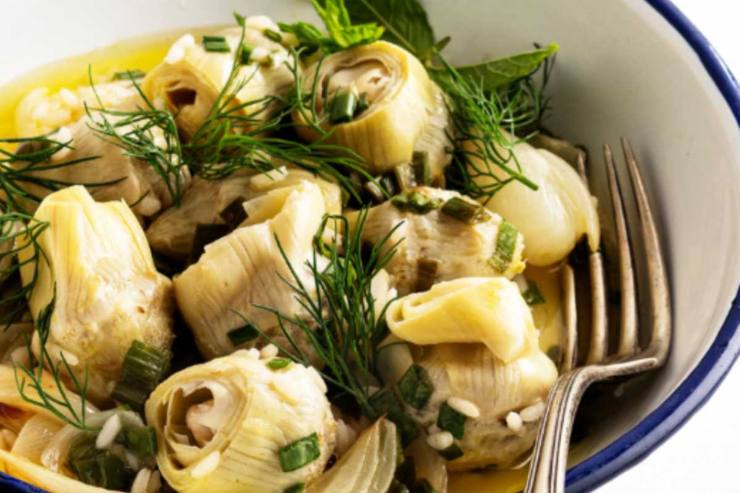 Sgoccioliamo per bene i carciofi e riversiamoli in una ciotola, lasciamo intiepidire e poi uniamo l’emulsione di olio e aromi. Spolveriamo quindi il parmigiano grattugiato e, se serve, aggiustiamo il sale.